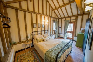 A bedroom with a large bed, wooden beams, a small round table, and a green cabinet. - Deberri - sleeps 8 guests  in 4 bedrooms (Fressingfield)