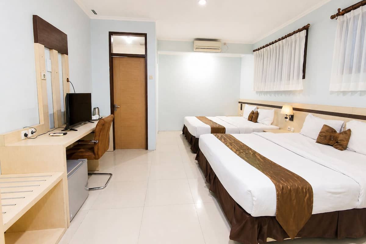 A hotel room with two beds, a desk with a computer, a chair, and a door.