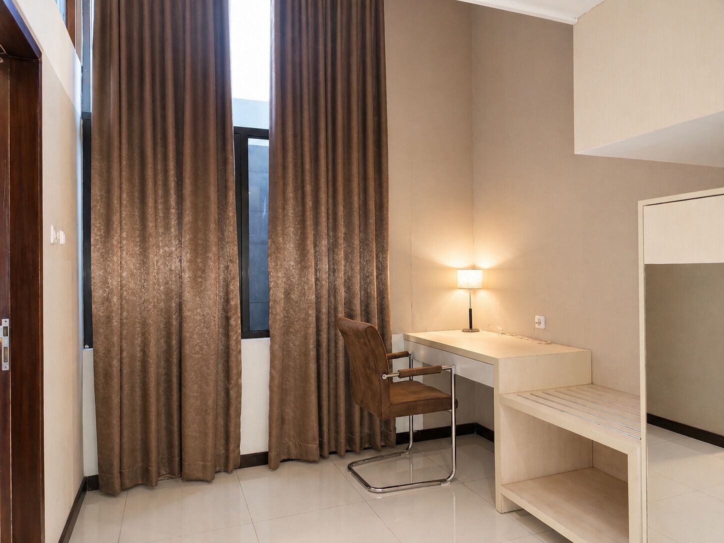 Une chambre d’hôtel équipée d’un bureau, d’une chaise et d’un lit avec une tête de lit.