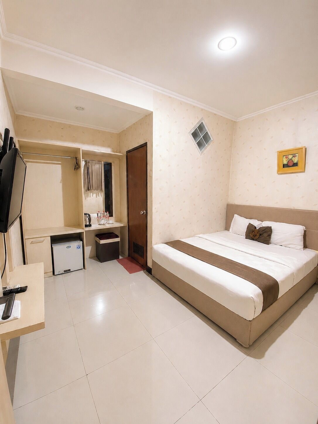 Een hotelkamer met een bed, een bureau, een kledingkast, een kleine kitchenette en een televisie.