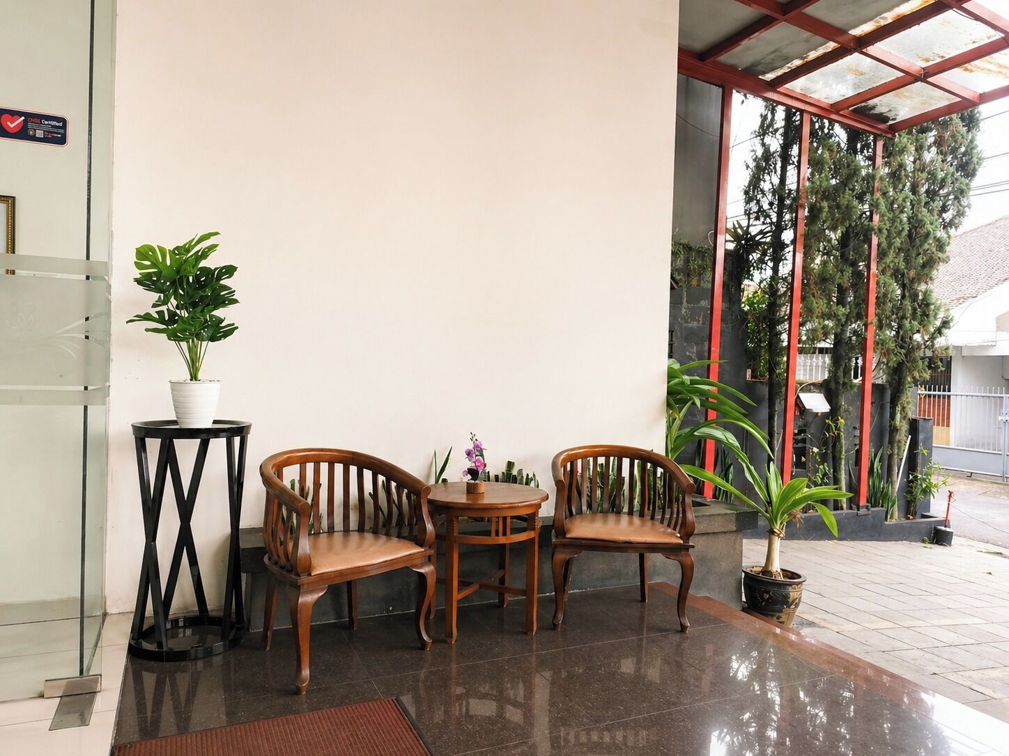 A reception area with two wooden chairs, a small table, and a potted plant.