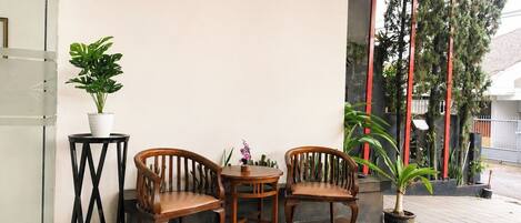A reception area with two wooden chairs, a small table, and a potted plant.