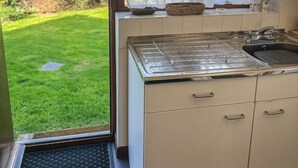 A kitchen with a window, a sink, and a small window sill with items. - Hideaway near the sea - sleeps 6 guests & welcomes 2 dogs (Scratby)
