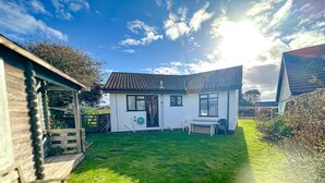 A house with a sloped roof, a small front yard, and a wooden deck. - Hideaway near the sea - sleeps 6 guests & welcomes 2 dogs (Scratby)
