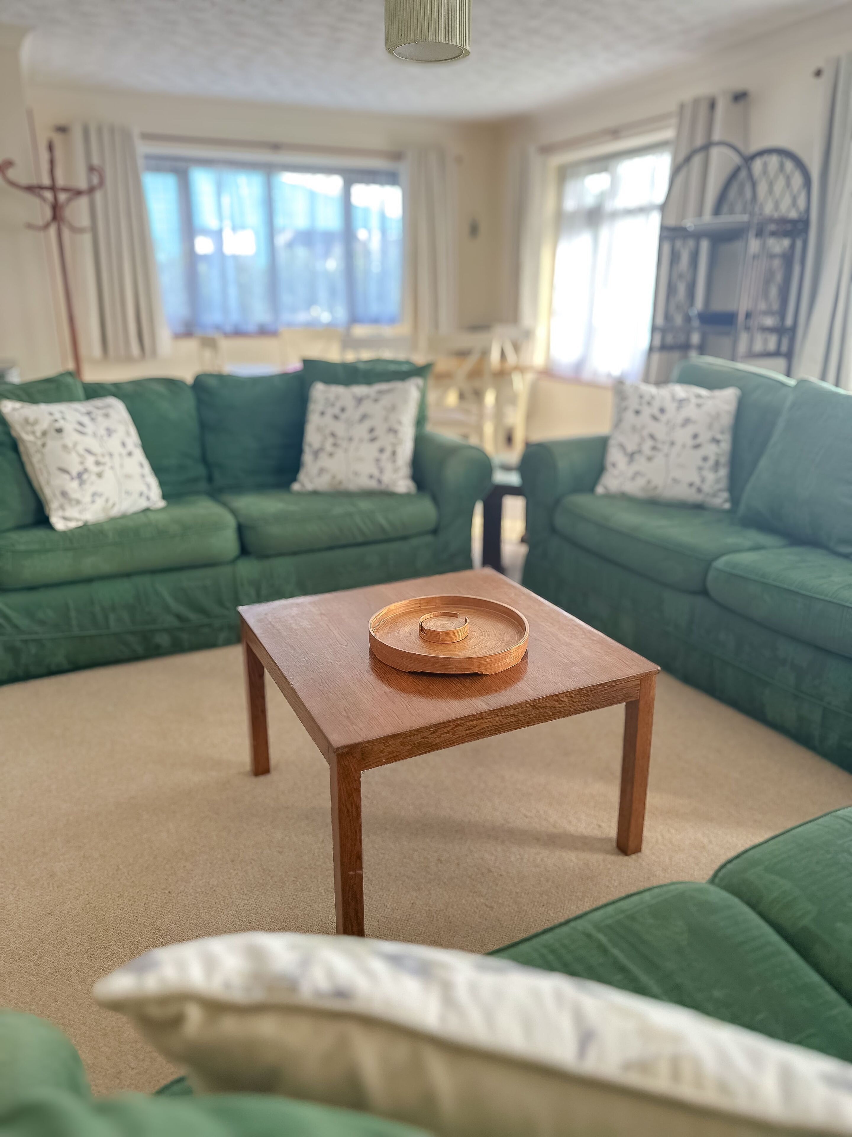 A living room with two green sofas, a wooden coffee table, and a patterned throw pillow.