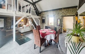 A spacious loft with a dining area, a staircase, and a stone wall. - Jolie maison avec piscine (Hestrud)