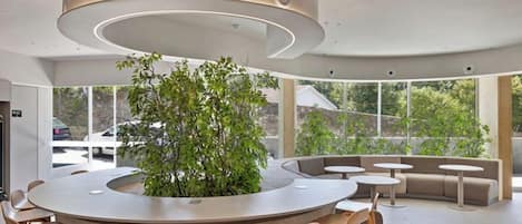 A modern interior with a central circular bar, seating area, and large windows.