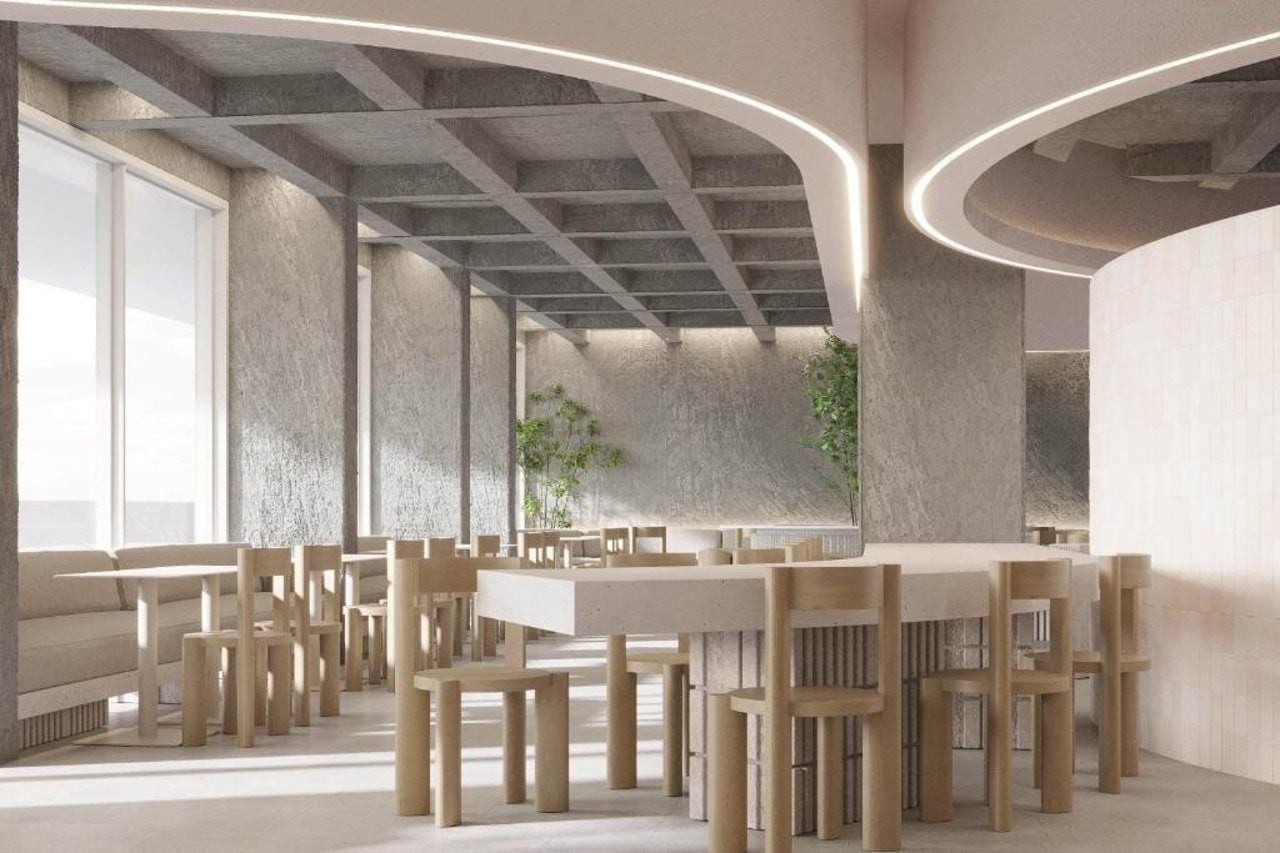 A modern interior with a central dining table surrounded by chairs, high ceilings with exposed beams, and large windows allowing natural light.