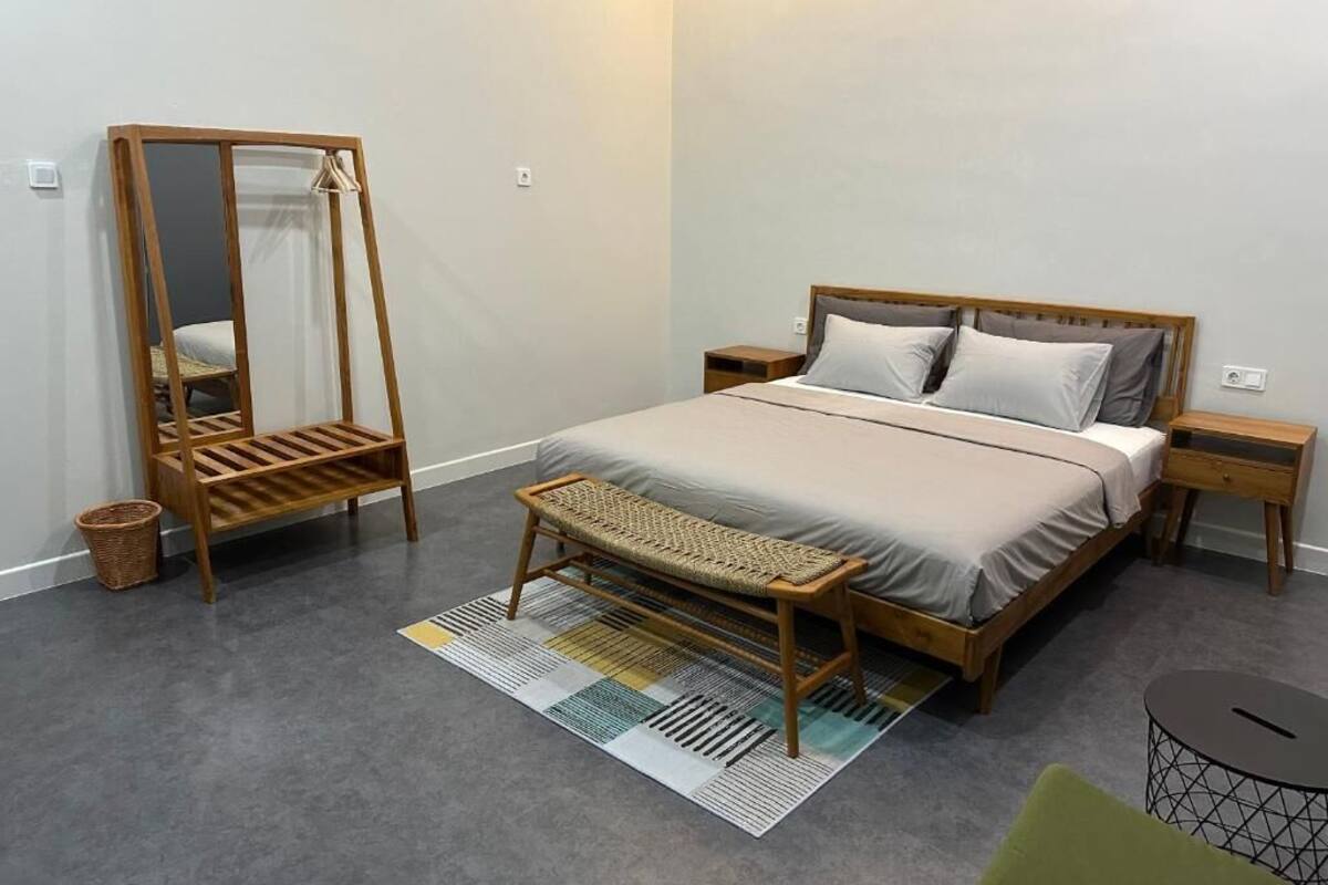A bedroom with a bed, bedside tables, a bench, a mirror, and a small round table.