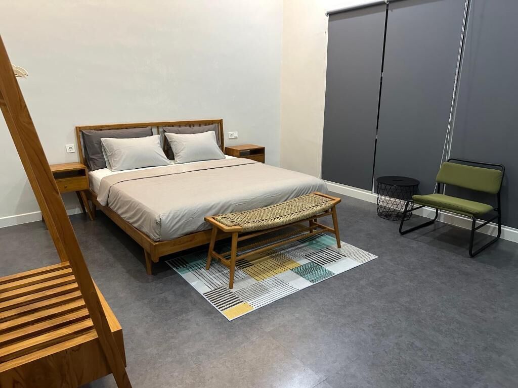 A bedroom with a bed, wooden bench, and a chair.