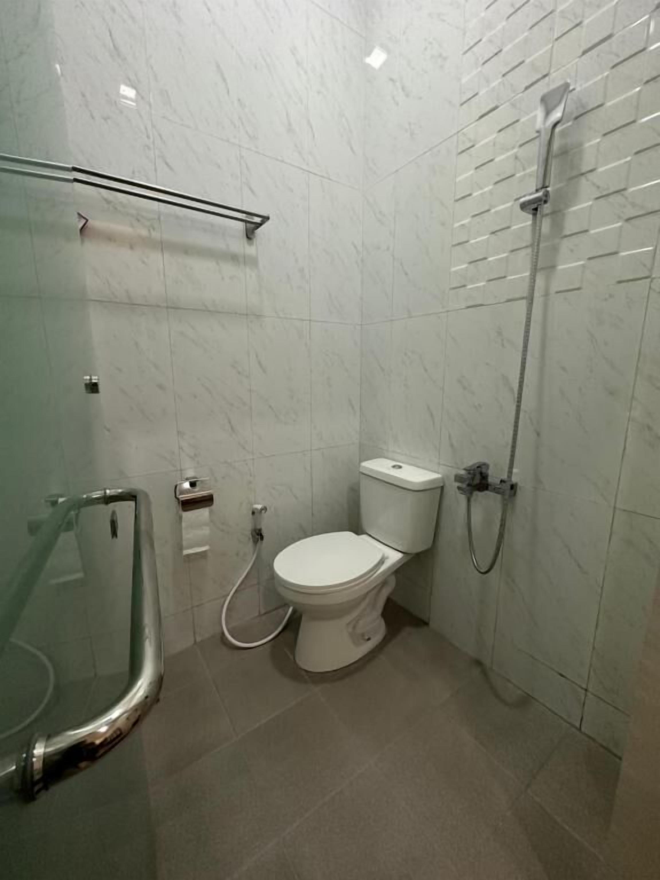 A modern bathroom with a toilet, shower, and glass-enclosed shower area.