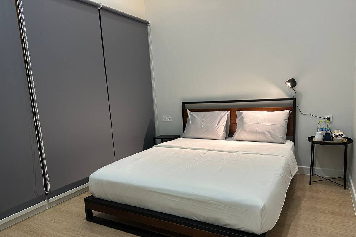 A modern bedroom with a bed, a nightstand, a lamp, and a wardrobe.