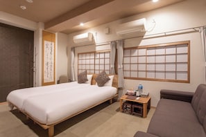A hotel room with a bed, a sofa, a small table with a bottle, and a wall-mounted air conditioner. - ROOM A Westernstyle triple room 30 m | 2 singl / Osaka City Ōsaka (Osaka City)