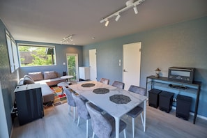 A modern living room with a dining table, sofa, and TV stand.