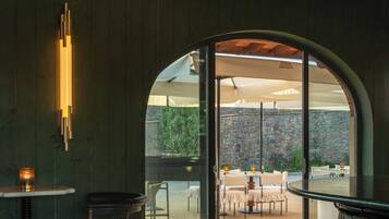 An interior space with a bar area, seating, and a view through an arched doorway to an outdoor patio.