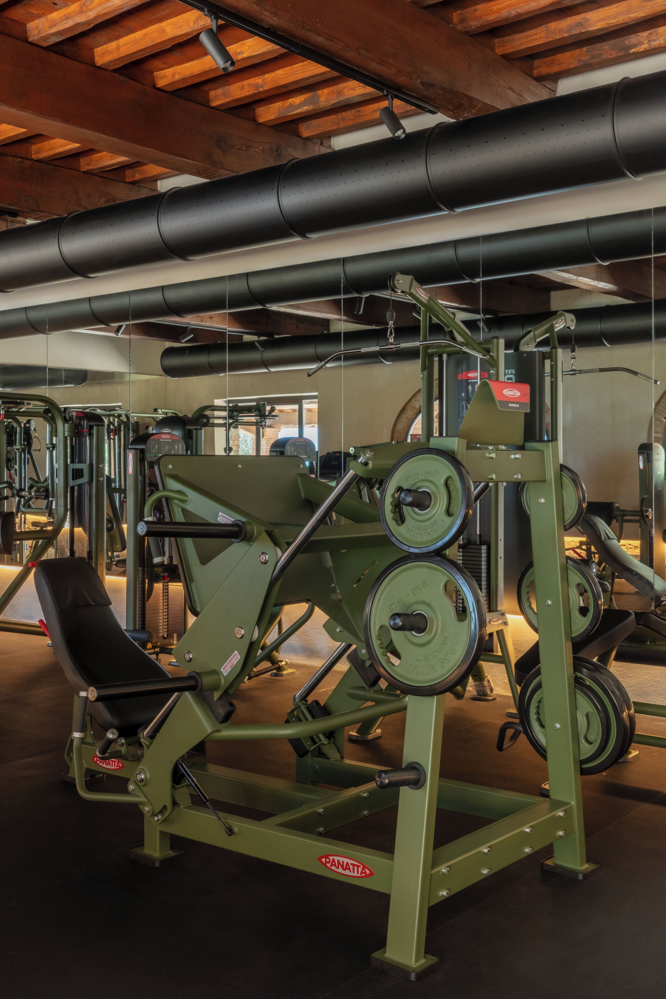 Ein Fitnessstudio mit Krafttrainingsgeräten, darunter ein Squat-Rack und Bänke.