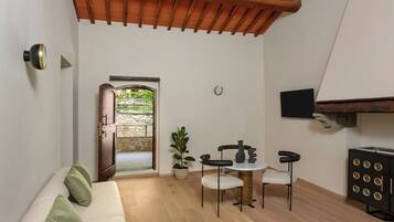 A compact living space with a wooden ceiling, a white sofa, a small table, a potted plant, and a cabinet with circular designs.