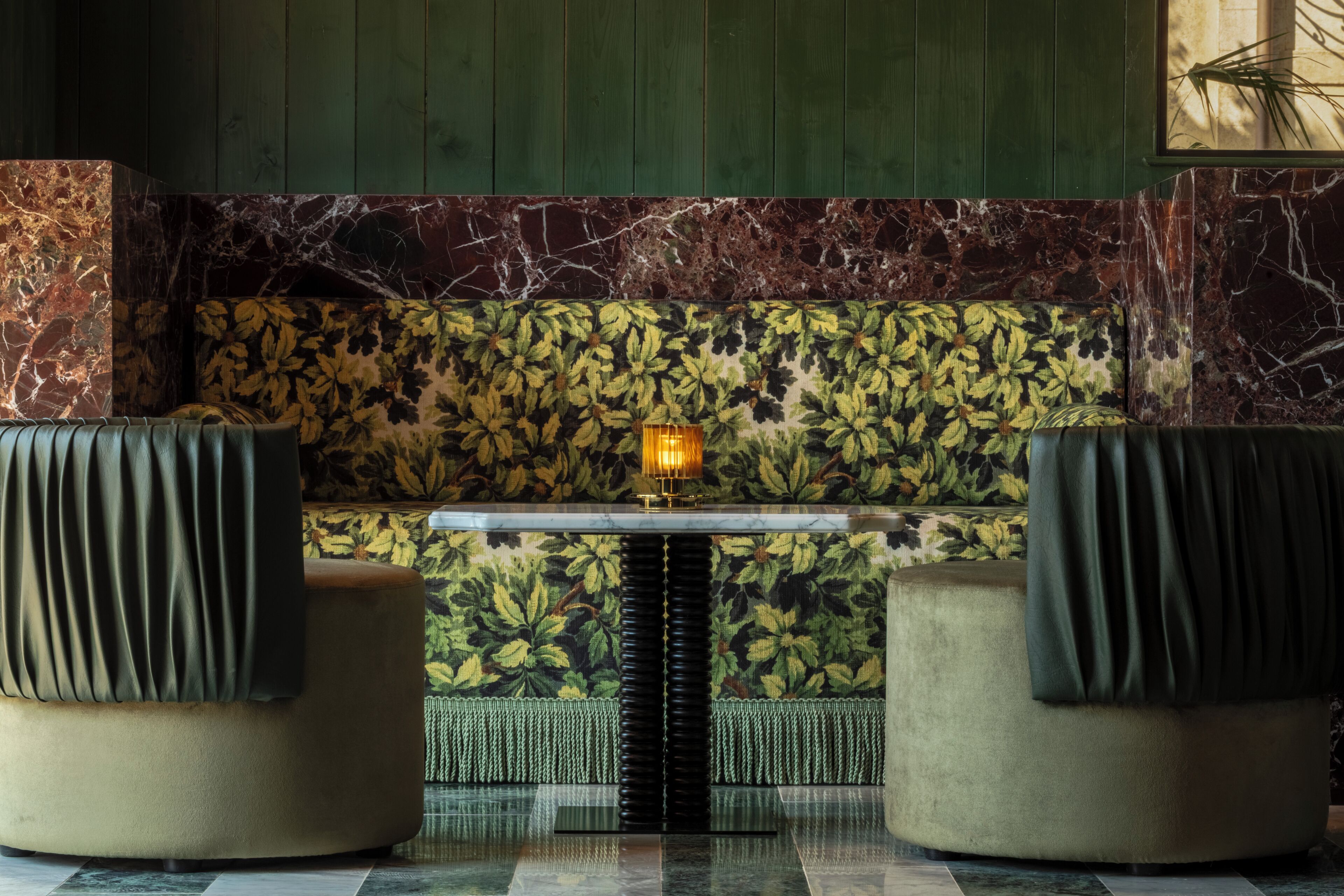 A seating area with a table and chairs, a patterned wall, and a green panel.