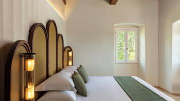 A room with a bed, a window, and a wall-mounted lamp.