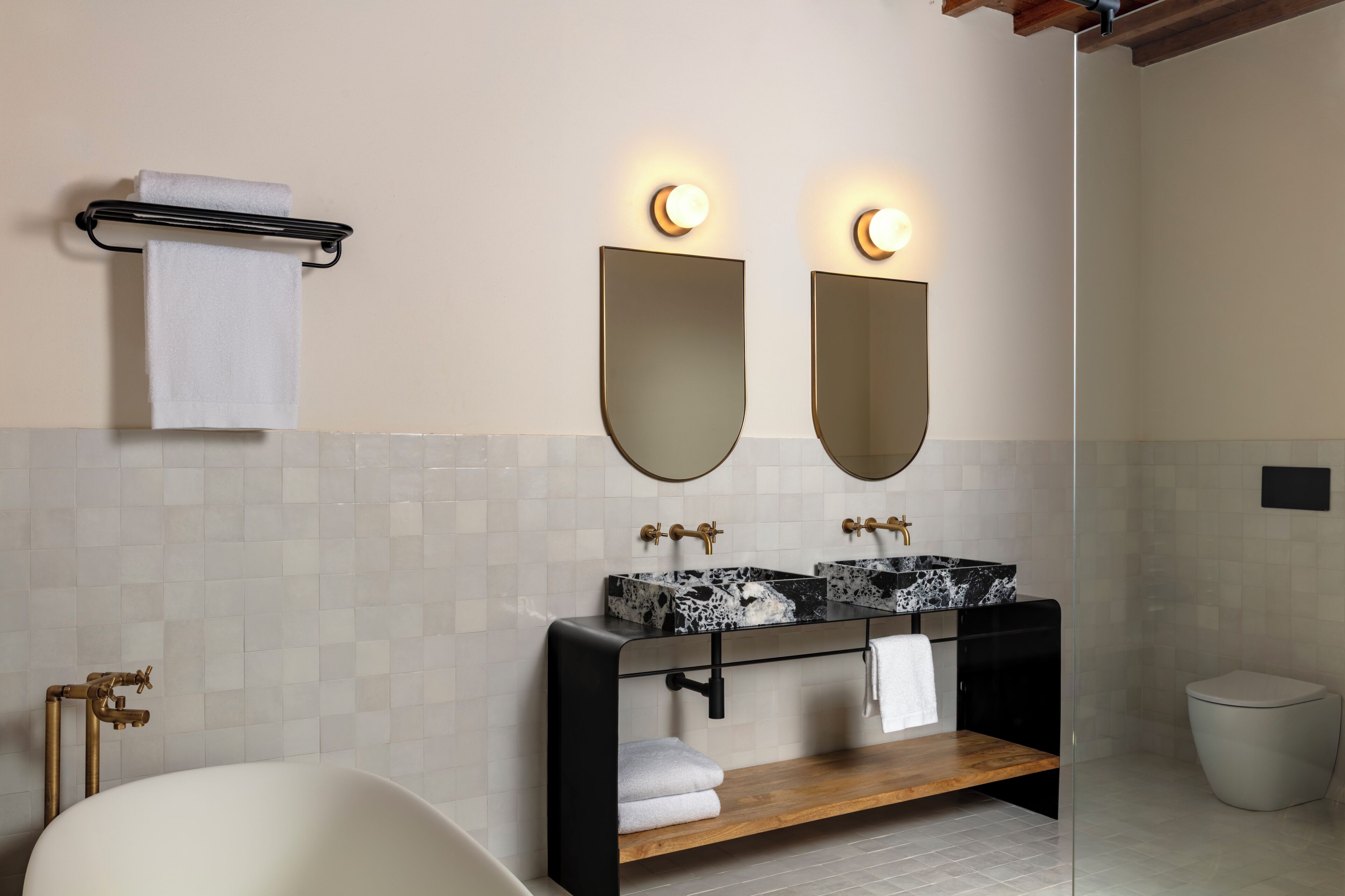 A modern bathroom with a bathtub, two sinks with marble countertops, and a large mirror above the sinks.