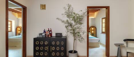 Quarto com teto de madeira, uma planta em vaso, um armário com garrafas e uma cama.