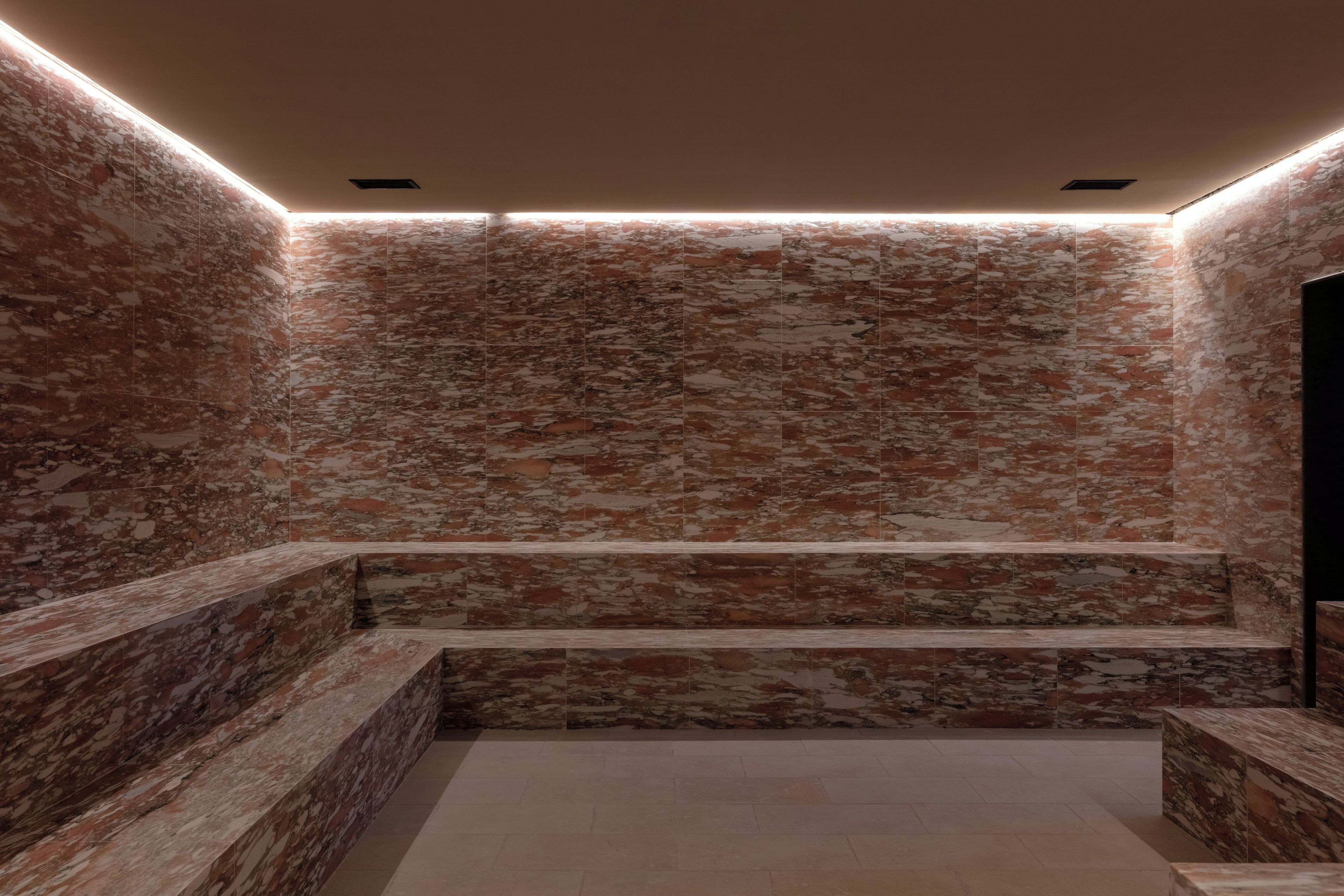 A spa area with a marble wall, a built-in bench, and a ceiling light fixture.