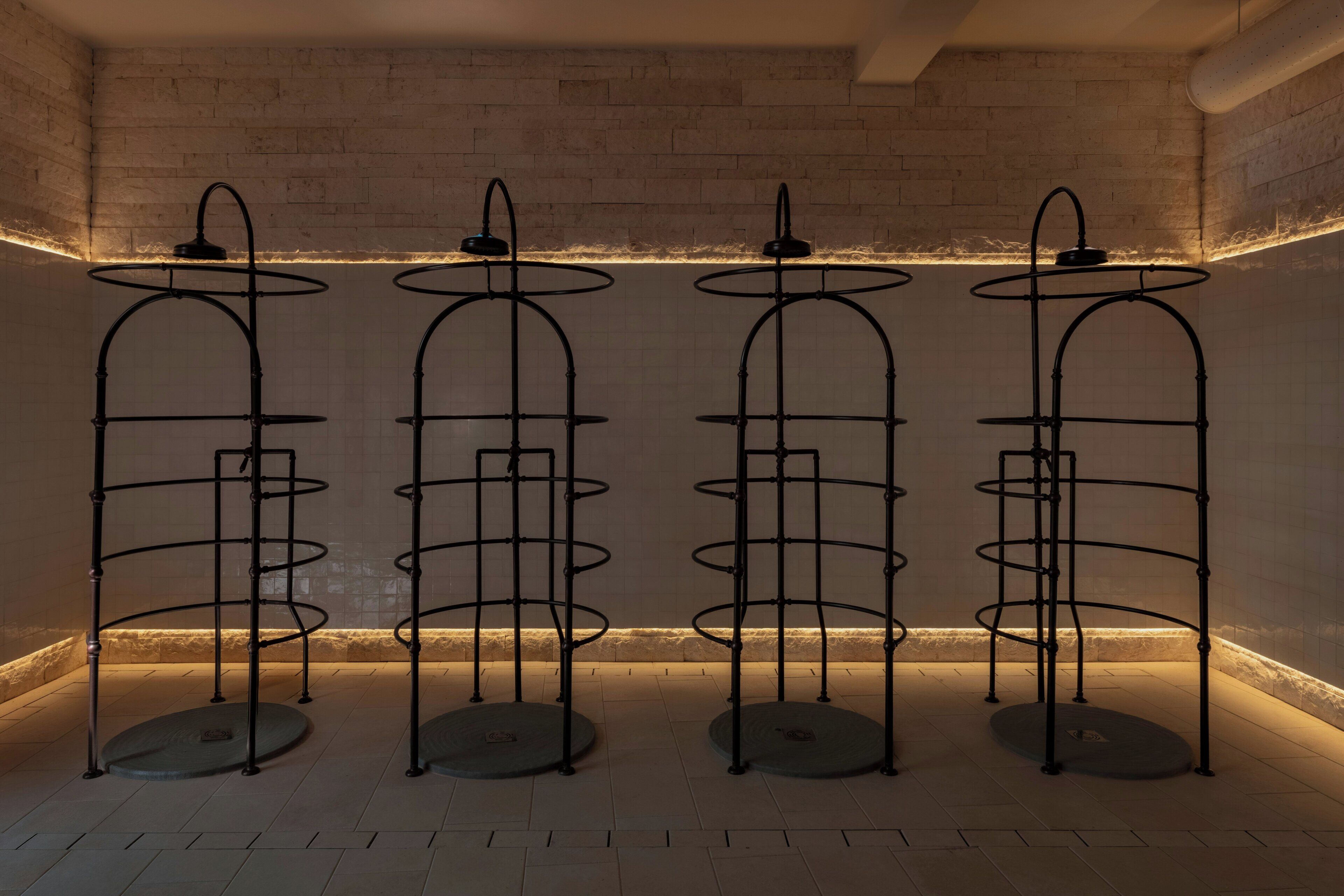 Four metal shelving units with circular platforms, arranged in a row against a tiled wall with a warm light strip.