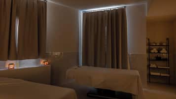 Una habitación con dos camas, un estante con toallas y una ventana con cortinas.