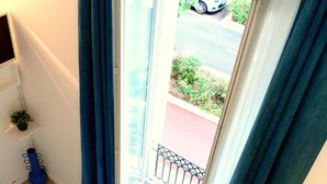 Ein Zimmer mit Blick auf eine Straße durch eine Glastür, ein kleiner Tisch mit einer Globus und ein blaues Kissen.