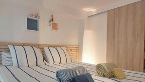 Ein Schlafzimmer mit einem Holz-Kopfteil, einem Bett mit gestreifter Bettwäsche, einem kleinen Fenster und einem Holzschrank.