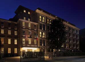 A multi-story hotel with a prominent entrance labeled 'THE CARLTON,' multiple windows, and flags.