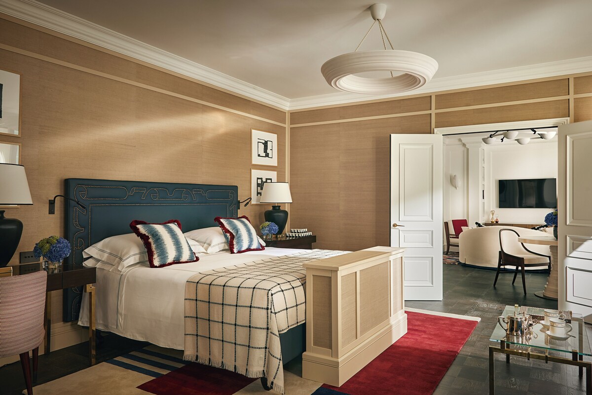 A hotel room with a large bed, a desk, a chair, and a mirror.