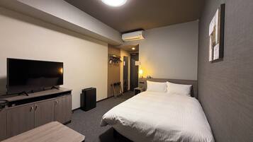Una habitación de hotel con cama, televisión, escritorio, armario y aire acondicionado.