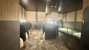 A public restroom with multiple urinals, a hand dryer, and a trash bin. - Hotel Route Inn Grand Maebashi (Maebashi)
