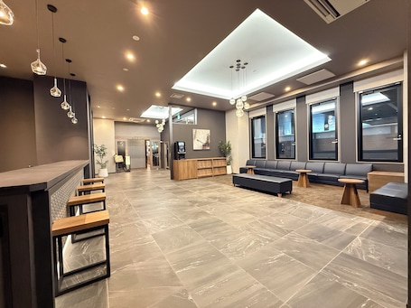 A modern lobby with a reception desk, seating area, and large windows.