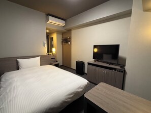 Una habitación de hotel con cama, televisión, escritorio, armario y aire acondicionado.