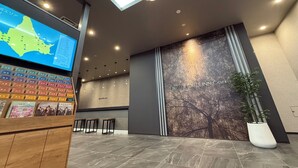 A modern hotel lobby with a digital map display, a reception desk, and a large wall mural. - Hotel Route Inn Grand Maebashi (Maebashi)