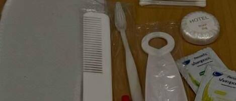 A hotel room with a bed, a toothbrush, a comb, a tube of toothpaste, a cup, and a small container.