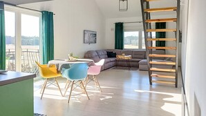 A spacious living area with a dining table, colorful chairs, a sofa, and a wooden ladder. - Lovely apartment in Szlachta with WiFi (Szlachta)