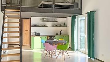 A modern kitchen with a dining area, a staircase, and a view of the outdoors.