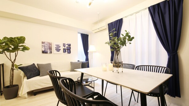 Una habitación moderna con cama, una mesa de comedor con sillas, una planta en maceta y obras de arte en la pared.