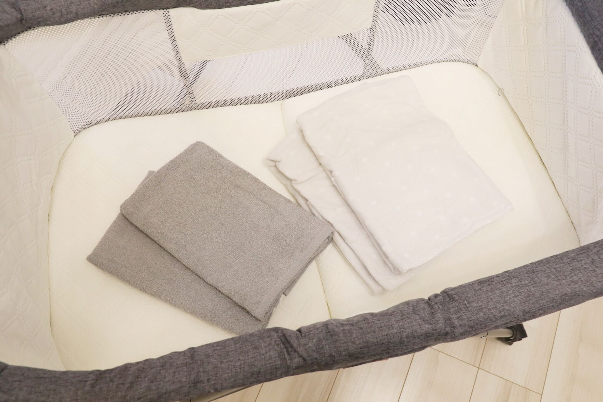 Ein ordentlich bezogenes Bett mit einer grauen Laken und einer gefalteten weißen Decke.