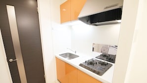 Cocina compacta con dos fregaderos, una estufa a gas y armarios color naranja.