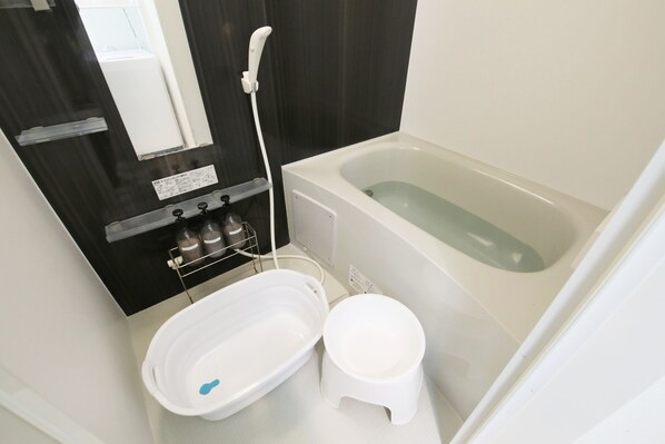 A bathroom with a bathtub, a toilet, and a small stool.