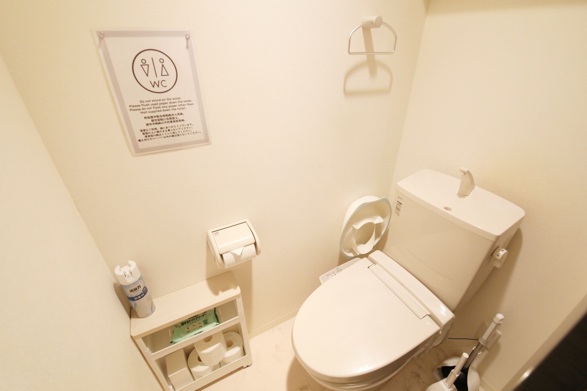 A small, clean bathroom with a toilet, a paper towel dispenser, and a toilet paper holder.