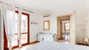 A bedroom with a bed, a dresser, a mirror, and a door leading to a balcony. - With private garden and air conditioning (Castelsardo)