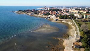 An aerial view of a coastal town with a sandy beach, a promenade, and residential buildings. - Garden Apartment in Umag (Umag)