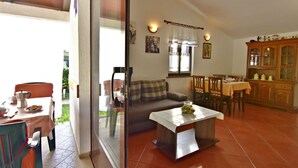 A living room with a sofa, dining table, and kitchen area with cabinets. - Garden Apartment in Umag (Umag)