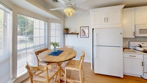 Una cocina con una mesa y sillas de madera, un refrigerador blanco y un ventilador de techo.