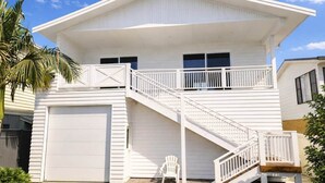 A white two-story house with a covered front porch, a garage, and a staircase leading to the upper floor. - 'Bentwood Escape' 
Modern unit in heart of Yamba (Yamba)